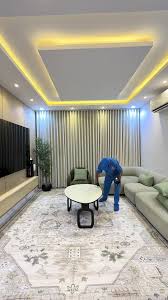 عامل من أفضل شركة تنظيف بمكة يقوم بتنظيف وتلميع طاولات و أثاث غرفة معيشة بعناية